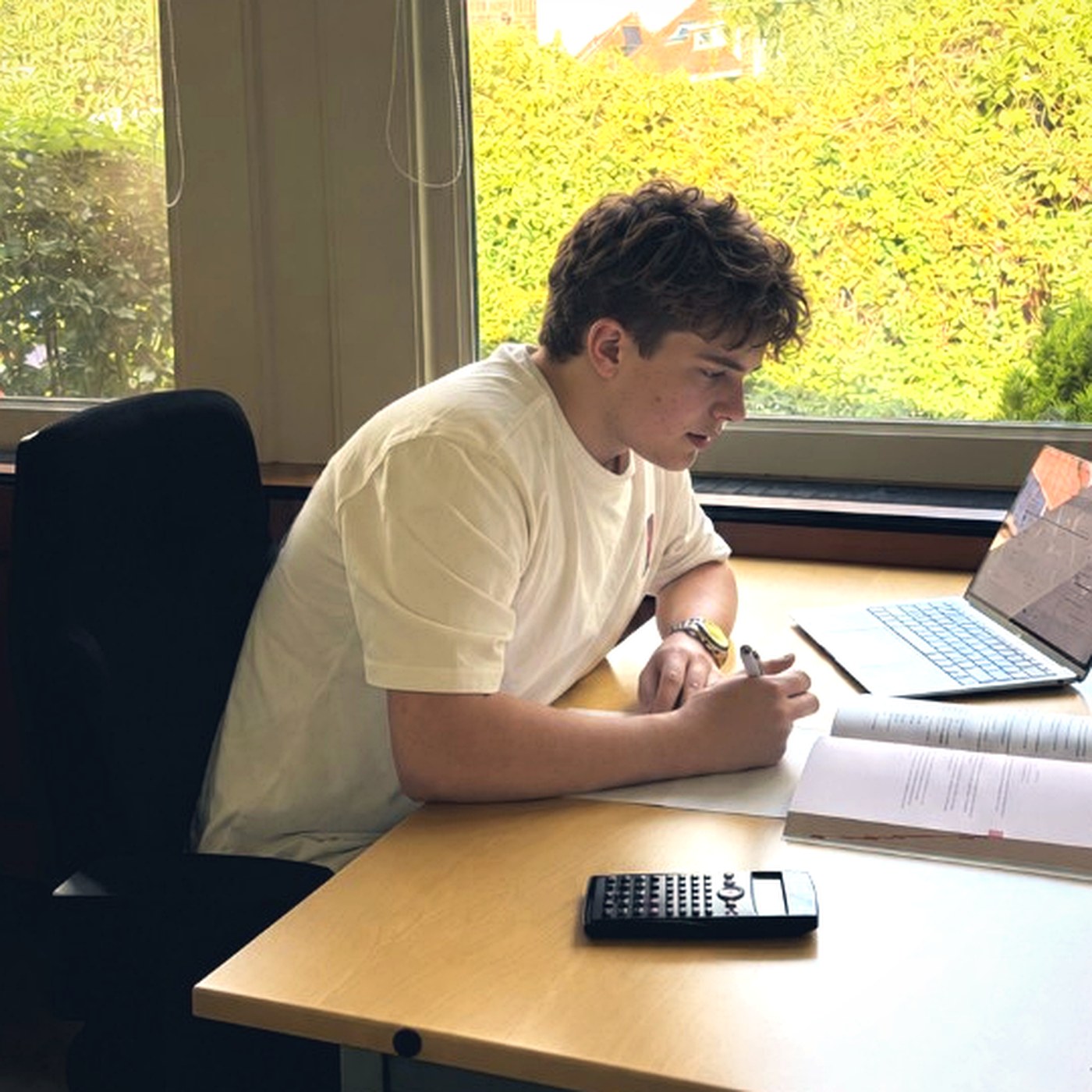 Leerling werkt zelfstandig aan huiswerk bij het raam